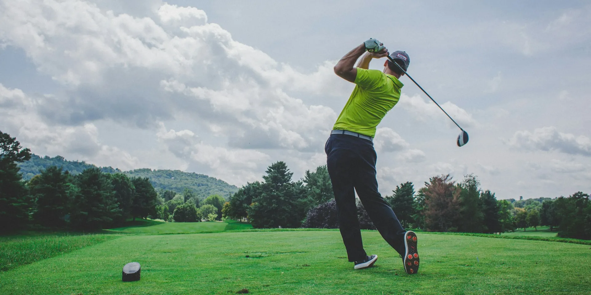 A golfer at the top of the backswing on the tee under an open sky